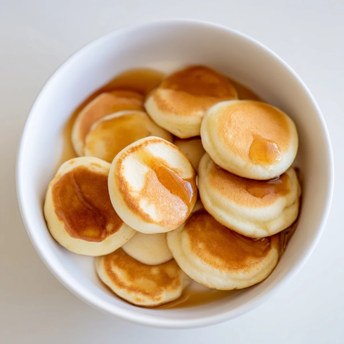 Close-up of golden Fluffy Pancake Cereal in a bowl, perfect breakfast with maple syrup.