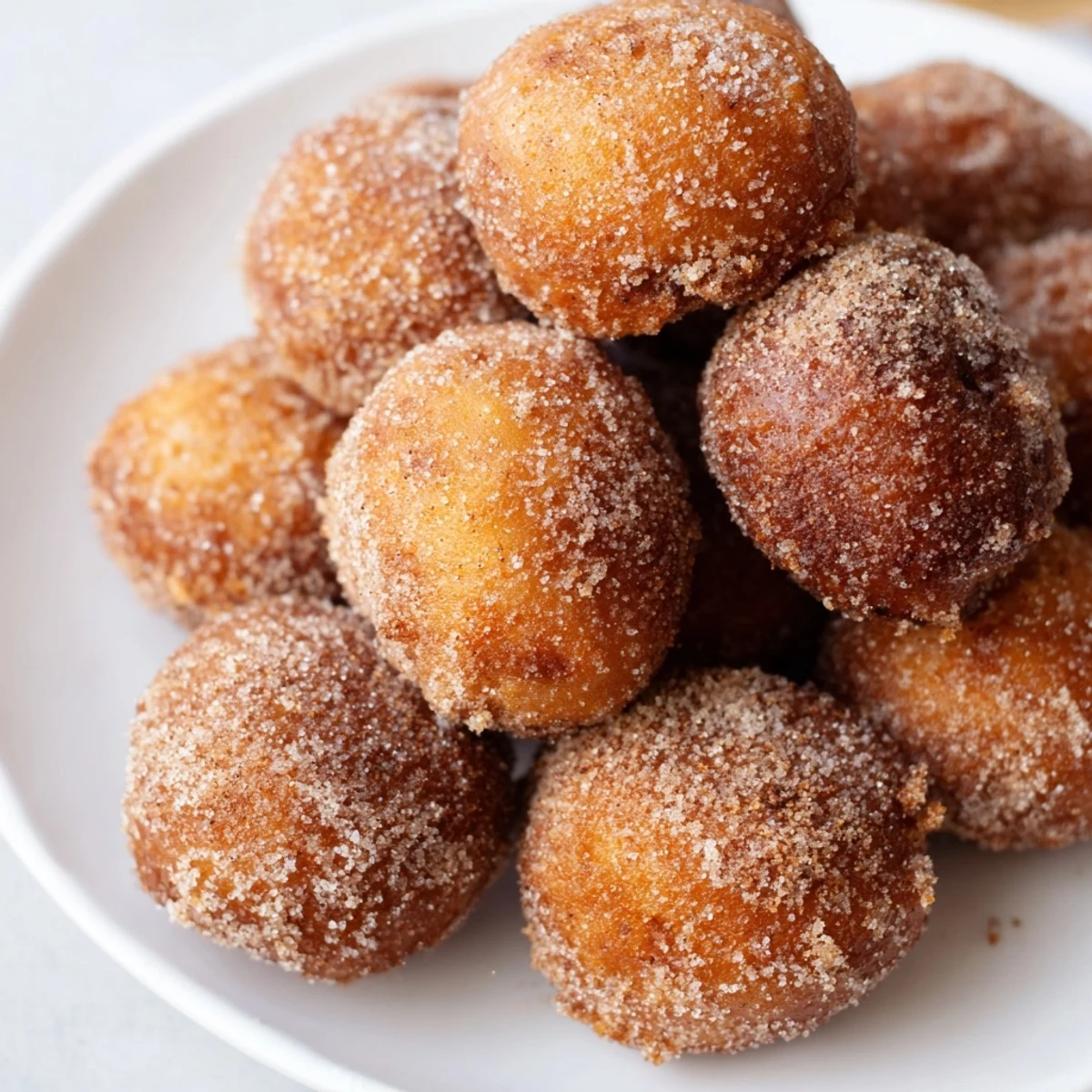 Warm, bite-sized air fryer cinnamon donuts, fresh from the basket, coated in a delightful cinnamon sugar glaze.