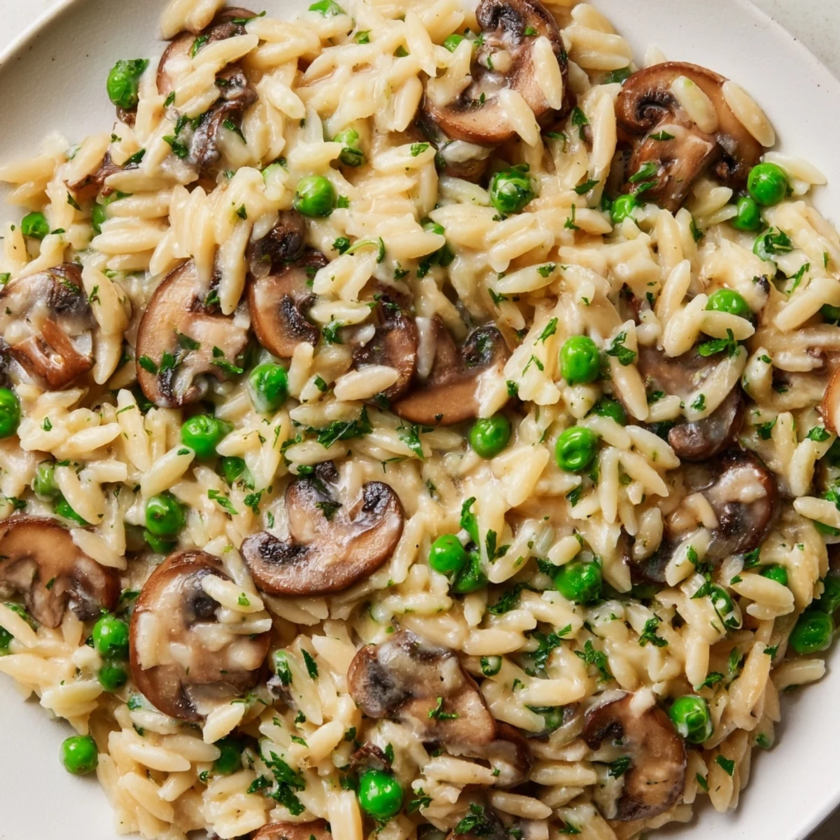 Steam rises from this orzo mushroom risotto-style dish, revealing tender cremini mushrooms and melted Parmesan for a comforting vegetarian dinner.