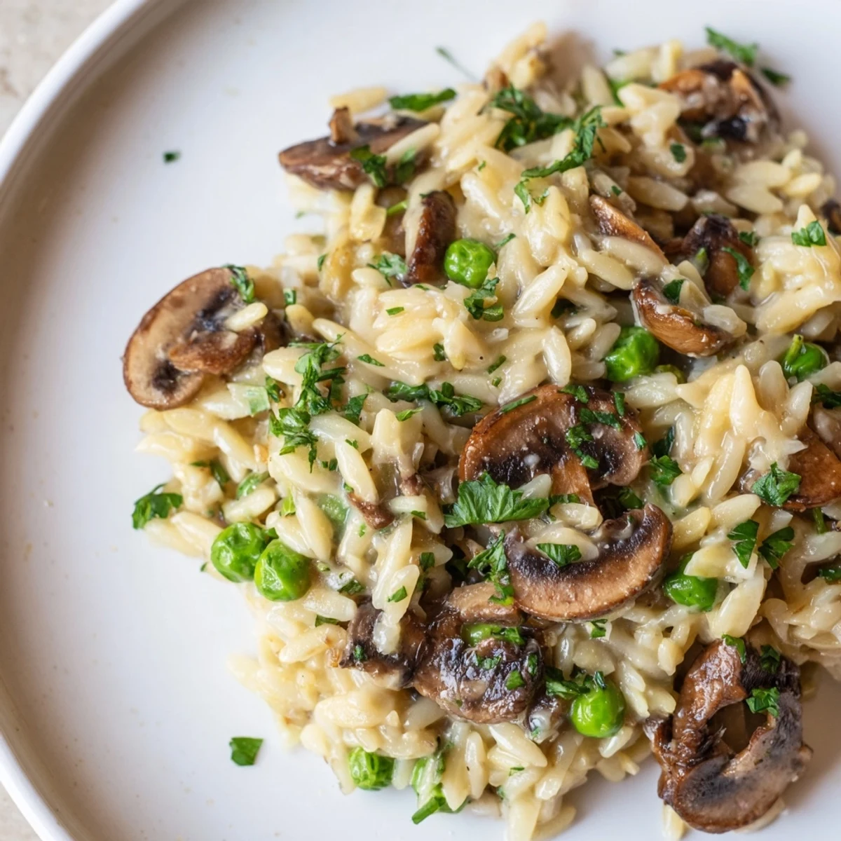 Serve orzo mushroom risotto-style garnished with fresh parsley and extra cheese, alongside a crisp green salad and glass of white wine.