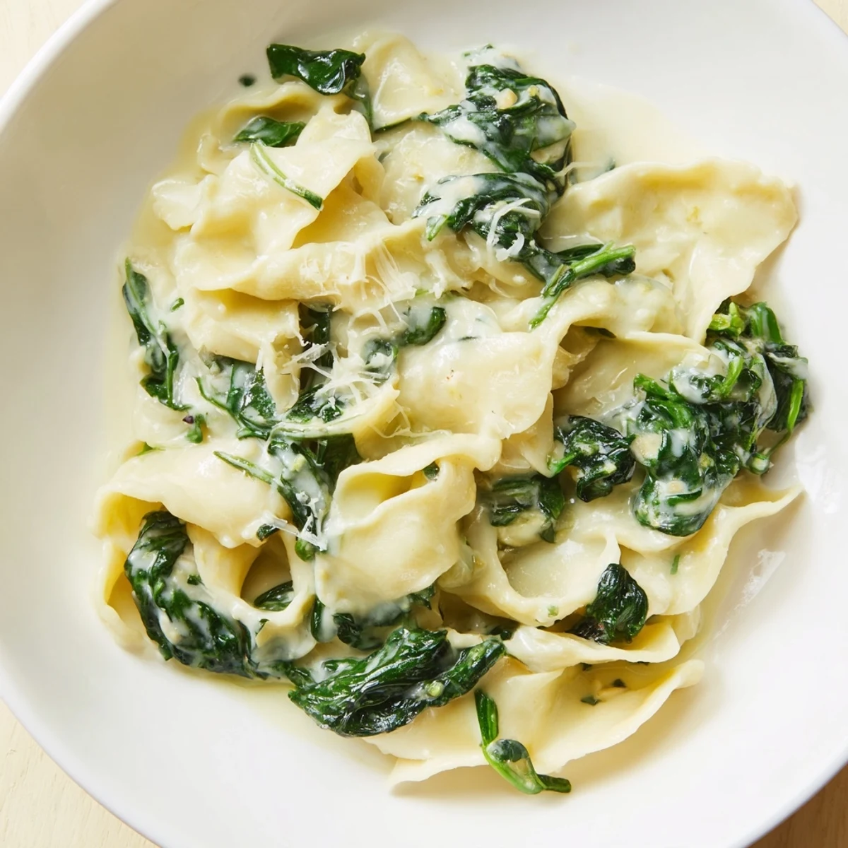 Creamy Spinach Garlic Noodles served warm in a skillet, glistening with rich parmesan cream sauce and flecked with vibrant green spinach.