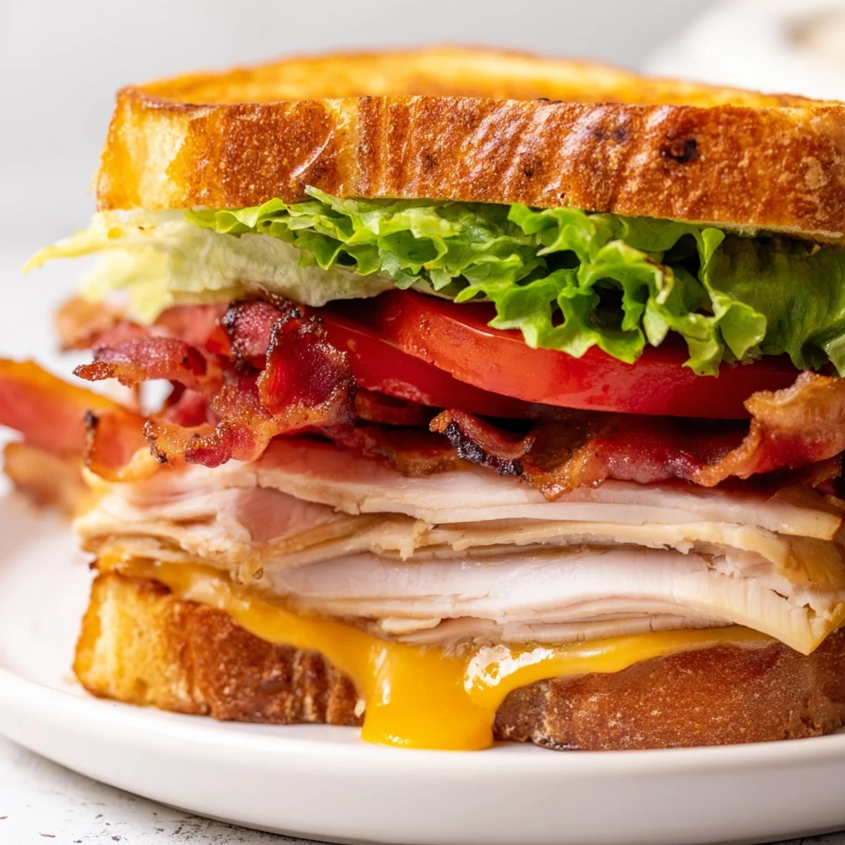Hot Turkey Club Grilled Cheese with melted cheese oozing from golden sourdough, served with a side salad.