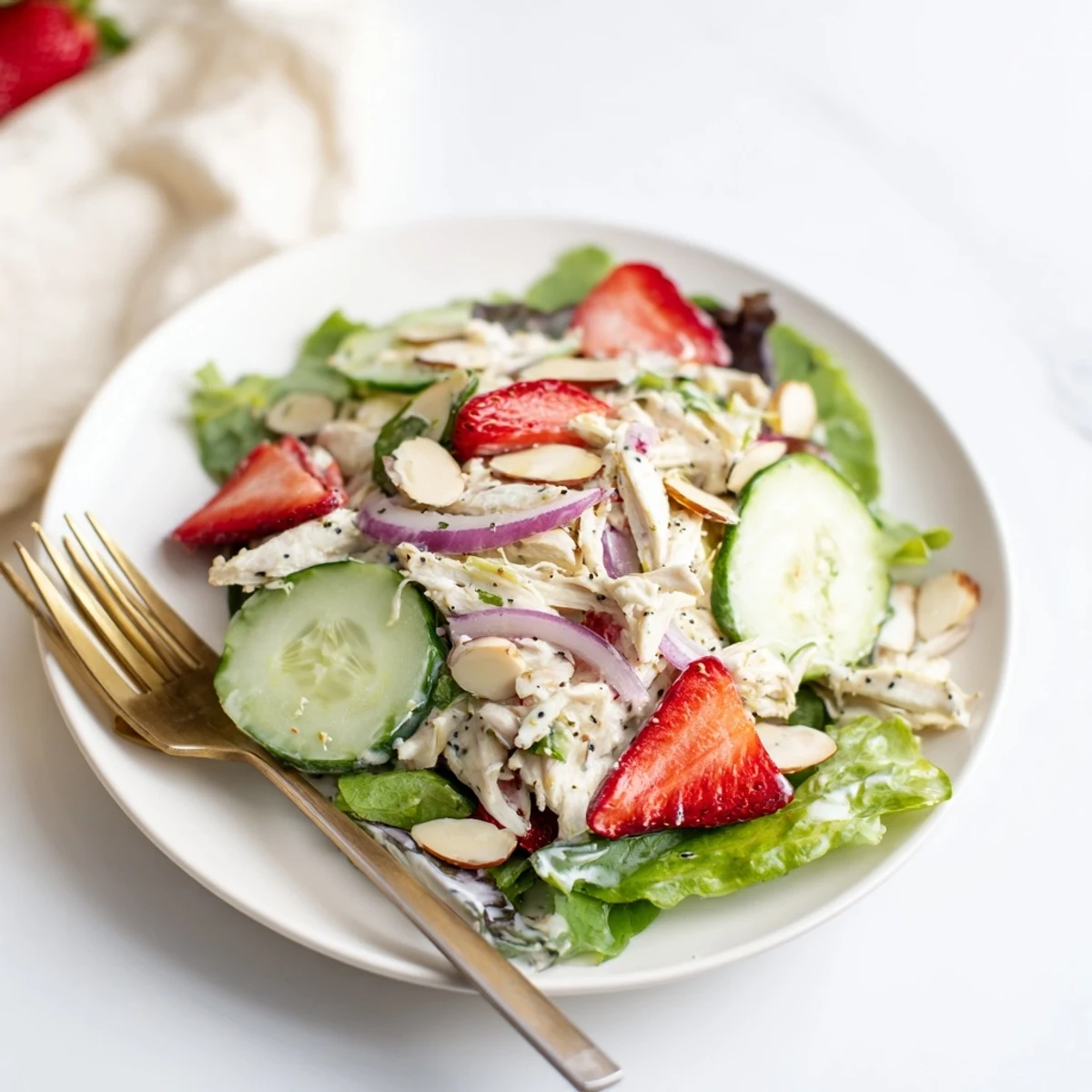 Freshly poached chicken breast slices mingle with sweet strawberries and crisp cucumber ribbons atop mixed greens in this vibrant Strawberry Poppy Seed Chicken Salad.
