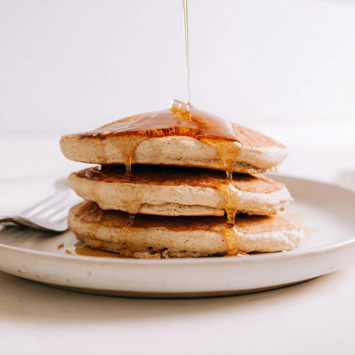 Fluffy Protein Power Pancakes stacked high on a plate, drizzled with maple syrup and topped with fresh berries.