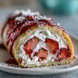 Golden crepes hold airy sponge cake and sweet berries, drizzled with white chocolate for a beautiful dessert.
