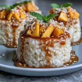 Individual servings of sweet sticky rice with coconut sauce and juicy mango, garnished with sesame seeds.  