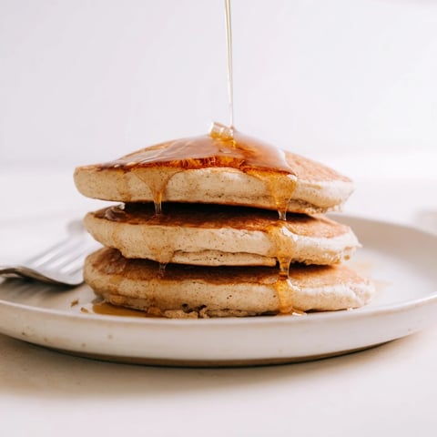 Fluffy Protein Power Pancakes stacked high on a plate, drizzled with maple syrup and topped with fresh berries.