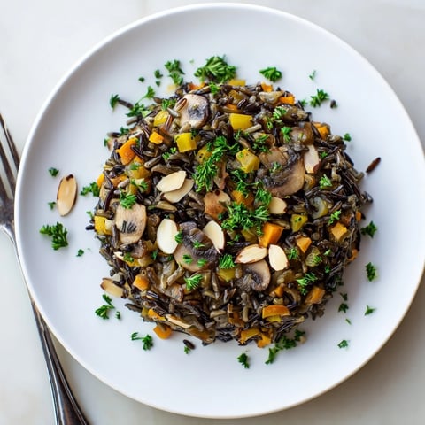 Warm Wild Rice and Mushroom Pilaf garnished with fresh parsley and toasted almonds in a rustic serving bowl.  