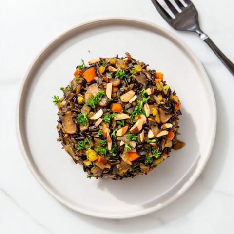 Hearty Wild Rice and Mushroom Pilaf with golden sautéed mushrooms, carrots, and celery, ready to serve.  