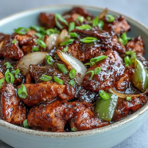 Black Pepper Chicken sizzles with sliced green bell peppers and minced garlic cloves.