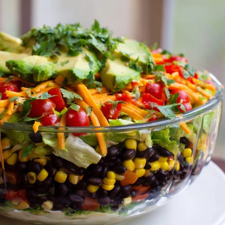 A clear glass bowl showcases the beautiful Southwest Sunset Palette salad with fresh cilantro and cheese.