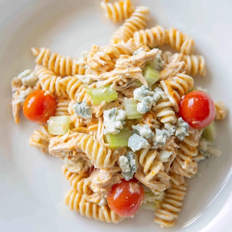 A savory Buffalo Chicken Pasta Salad tossed with tender chicken, pasta, and fresh herbs, served on a chilled plate.