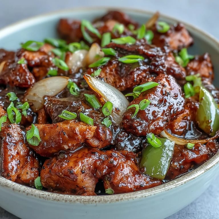 Black Pepper Chicken sizzles with sliced green bell peppers and minced garlic cloves.